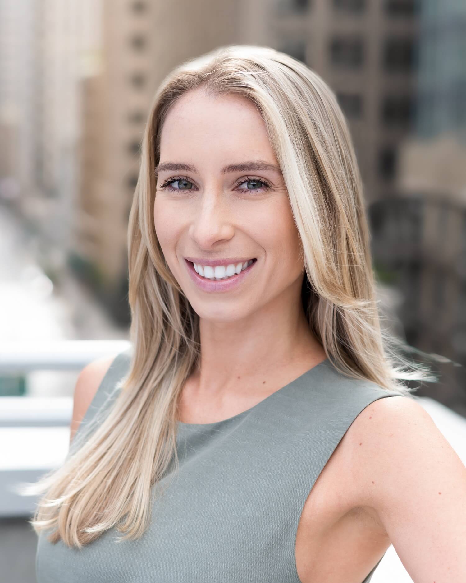 outdoor professional headshot of blonde young executive in urban setting